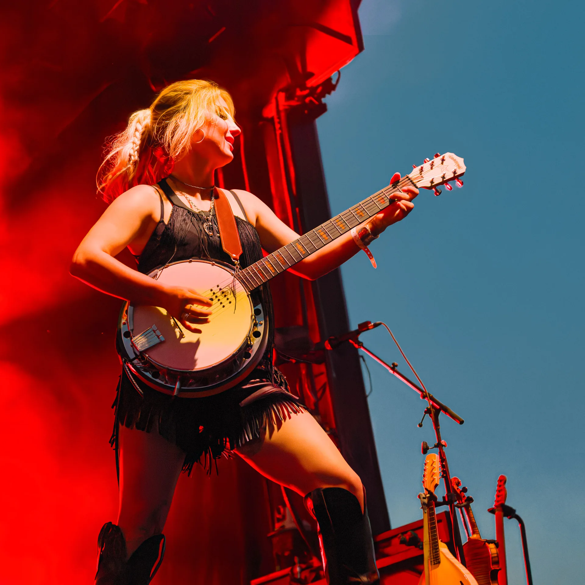 Artiste au banjo sur scène sous un éclairage rouge au festival Cigale
