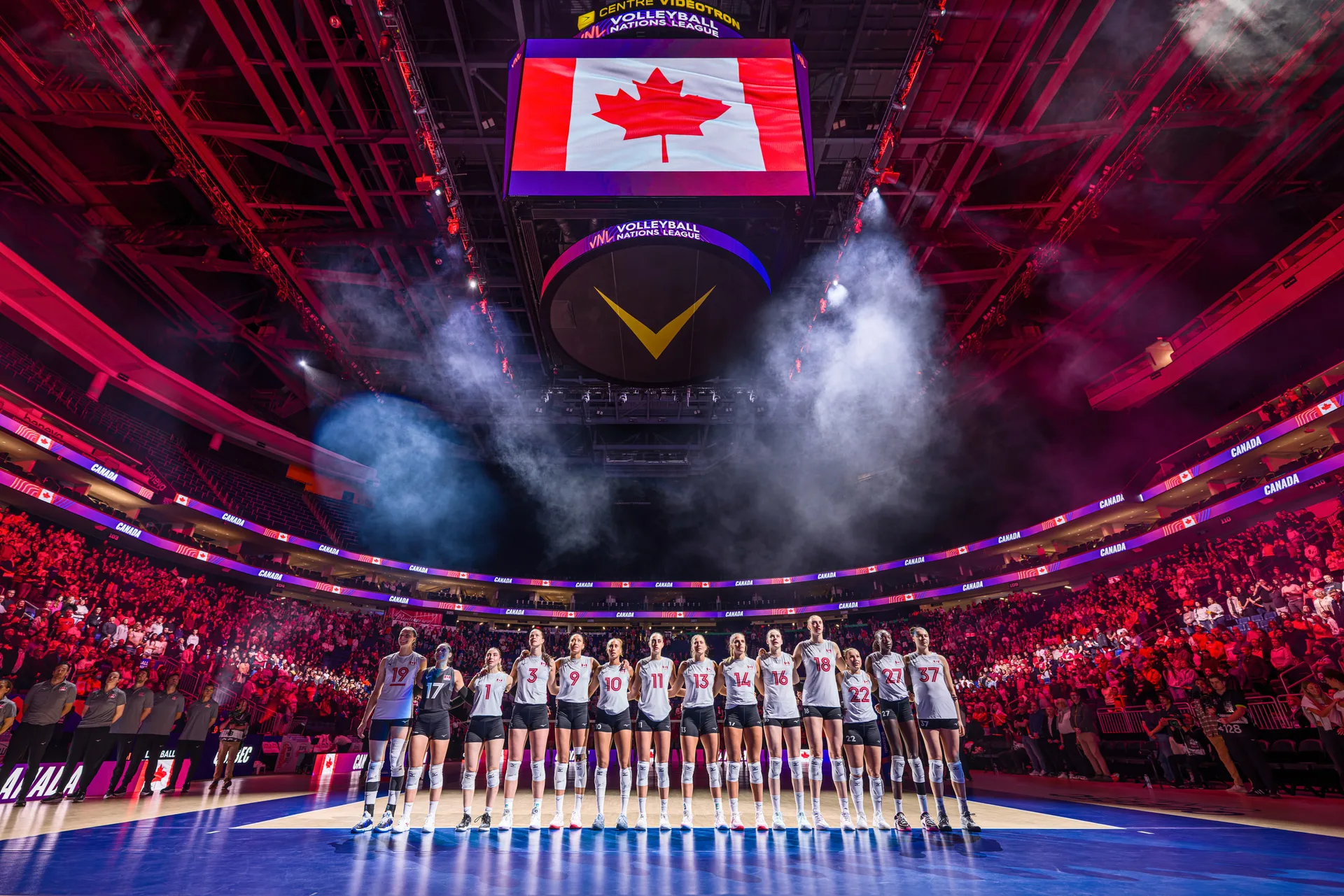 Alignement de l'équipe sur le terrain sous un grand drapeau canadien lors d'un match de la Ligue des Nations de Volleyball à Québec